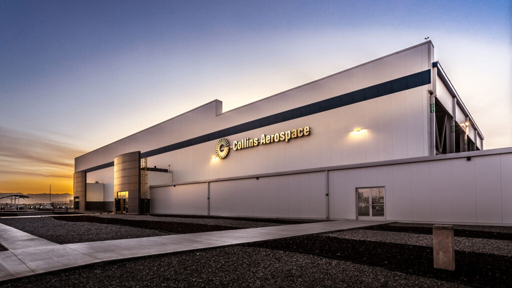 Front of Collins Aerospace facility at sunset|Material handling equipment outside the Collins Aerospace facility|Conference room in the Collins Aerospace facility|Restroom vanity with dual sinks and mirrors. White