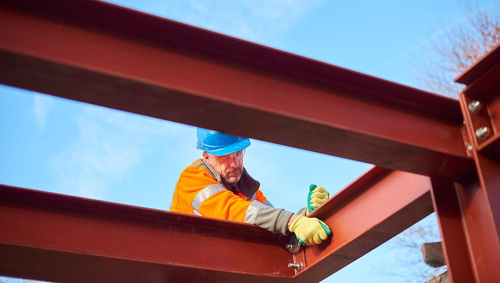 Construction worker assembling steel beams|