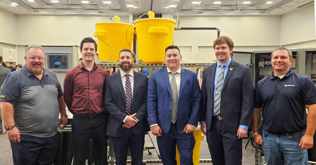 UNF Process Skid team members pose in front of their senior design project. From left are Greg Kline of Vega Americas; Daniel Fowler