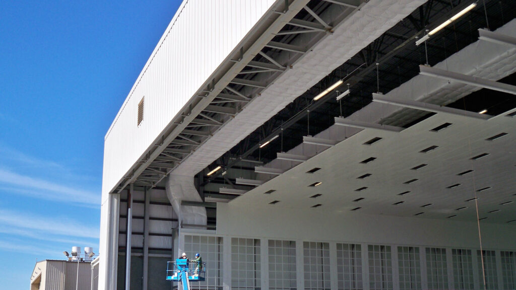 Exterior of Gulfstream Paint Hangar. Large white building and blue sky.